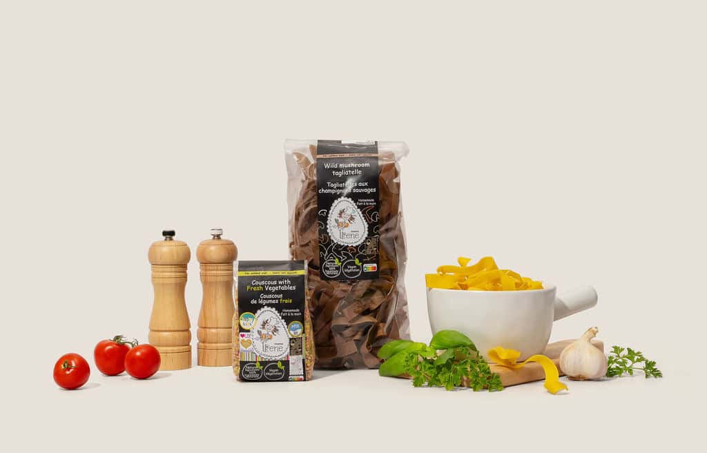 A bag of mushroom pasta, next to a bowl of tagliatelle and vegetables.